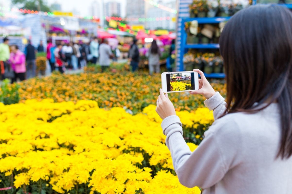 woman takes a picture of bright yellow bouquets at lunar new year flower market in hong kong