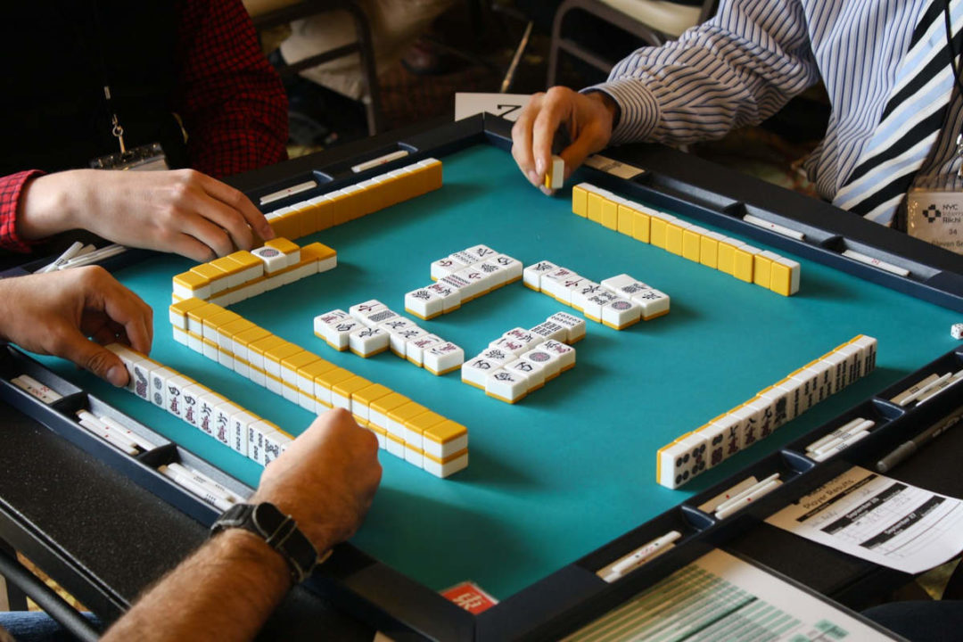 four pairs of hands playing mahjong