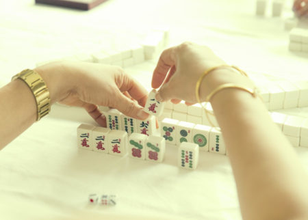 hands with gold jewelry assembling mahjong melds