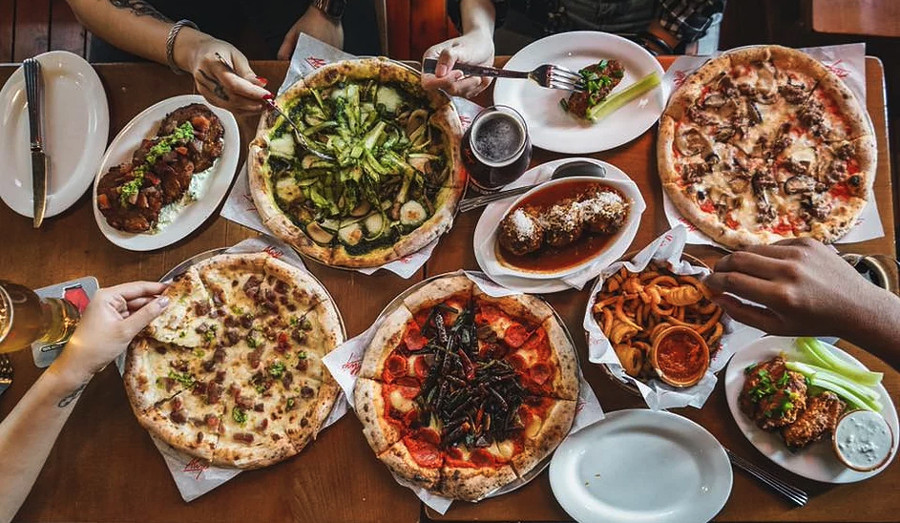 table full of pizzas and side dishes at alvys hong kong