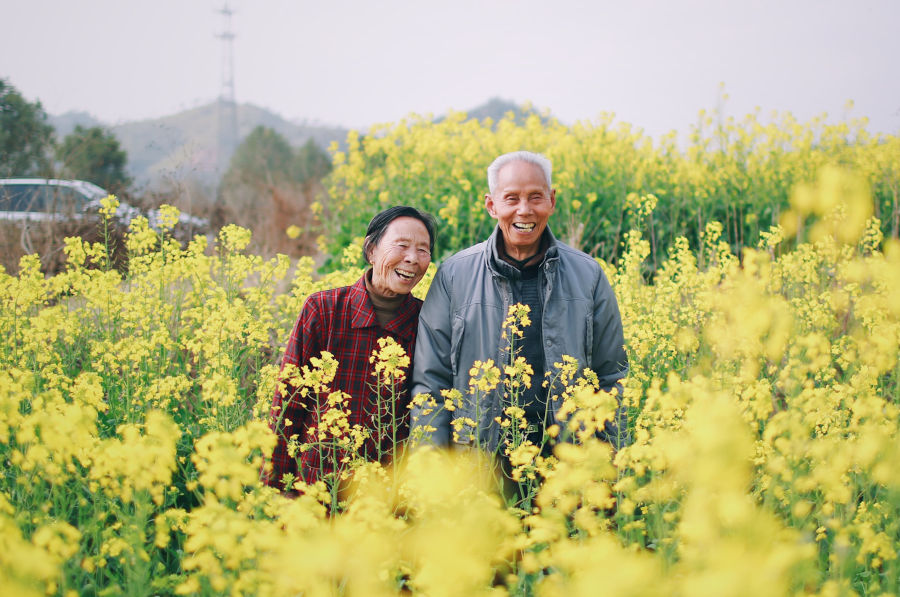 two chinese elderly people laughing in a flower field