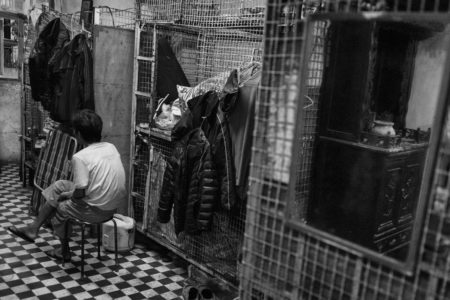 resident beside his tiny cage home in hong kong