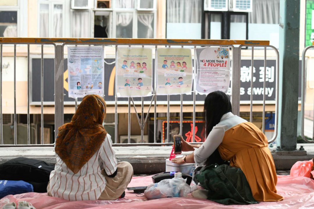 domestic helpers sit on plastic sheets on a bridge in hong kong
