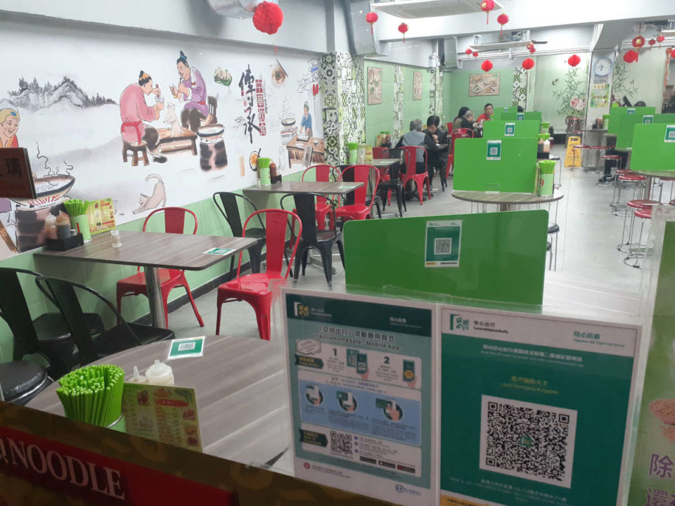 view through the window of a hong kong restaurant with leavehomesafe qr code on it