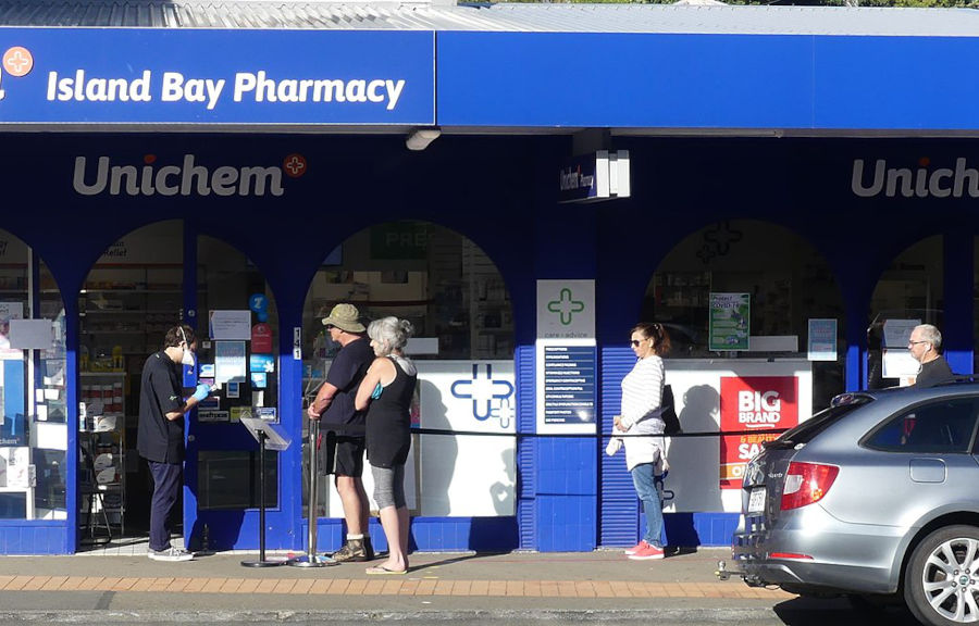 people line up outside a pharmacy in wellington new zealand for a vaccine