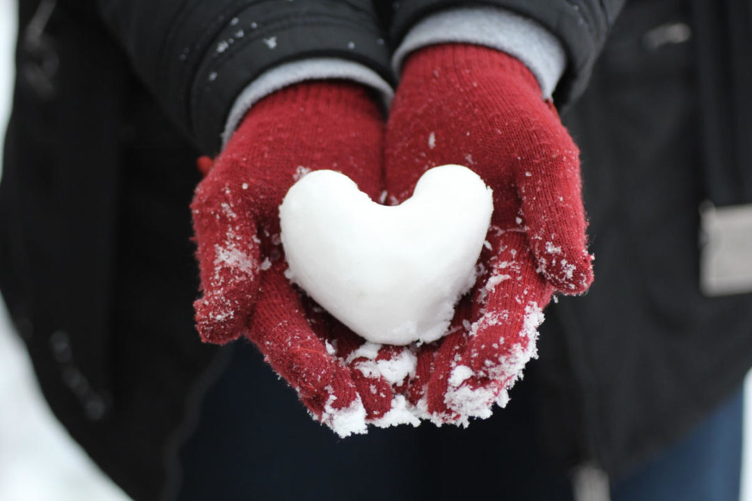 red gloved hands holding a snow heart