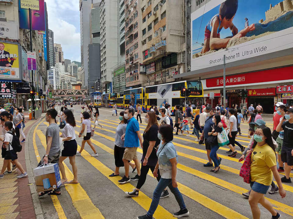pedestrians wearing masks cross hong kong street