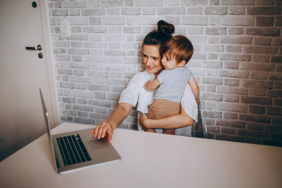 parent working on laptop while carrying child