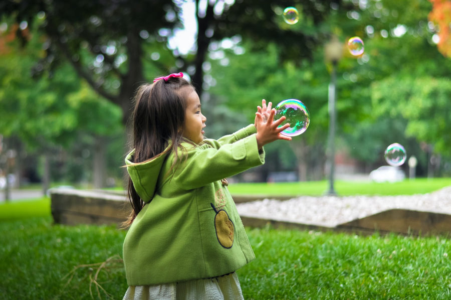 child playing with bubbles outside