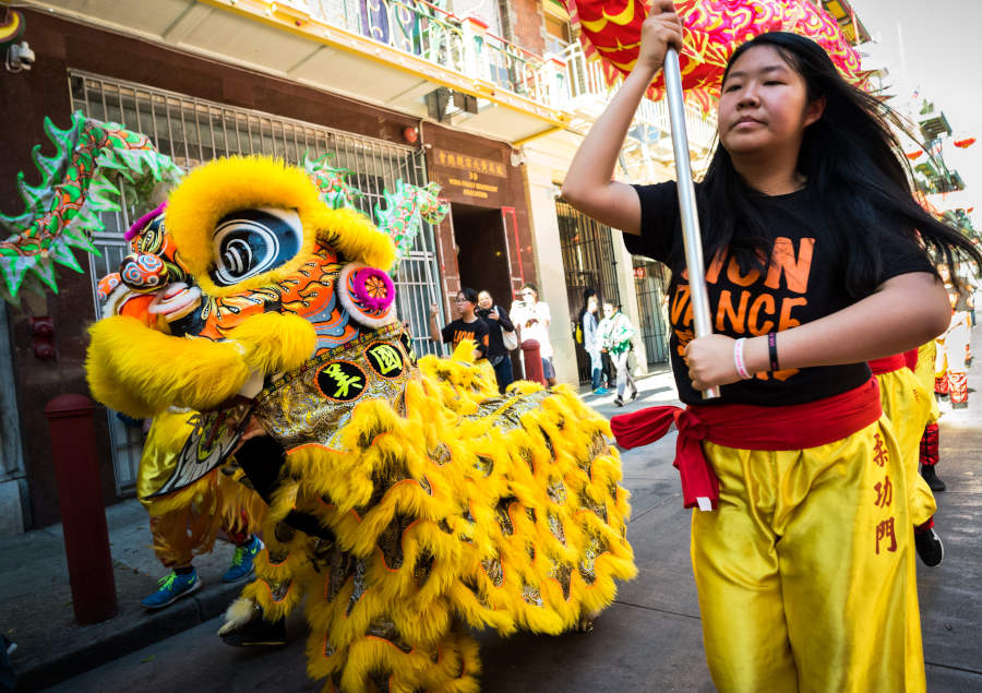 lion dance beside a woman holding up a pole connected to dragon dance