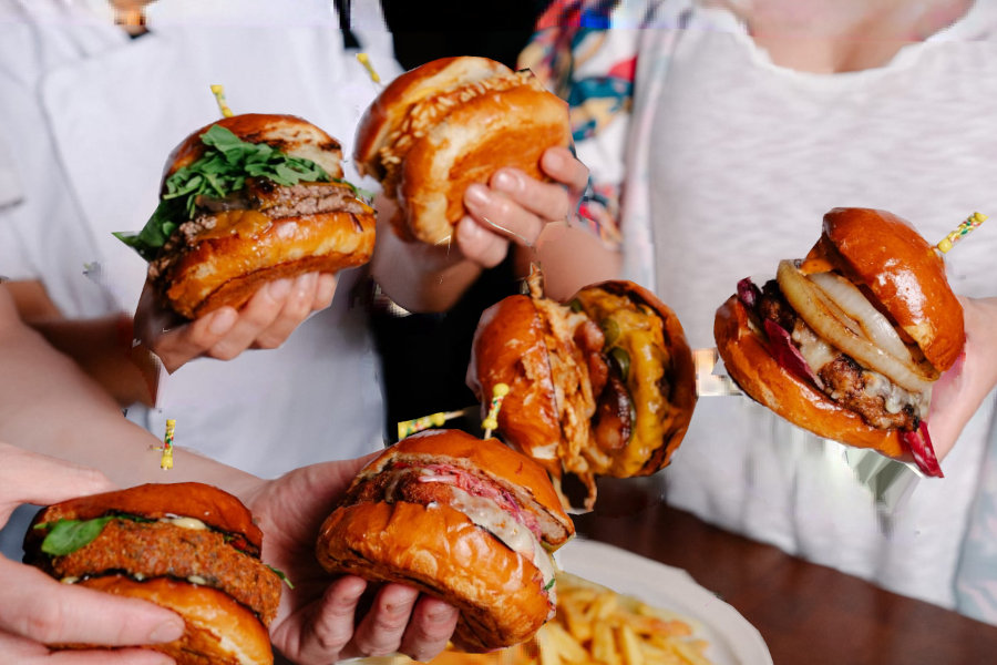 hands holding burgers from feather and bone hong kong