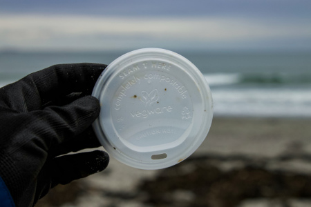 plastic coffee lid with 'completely compostable' label