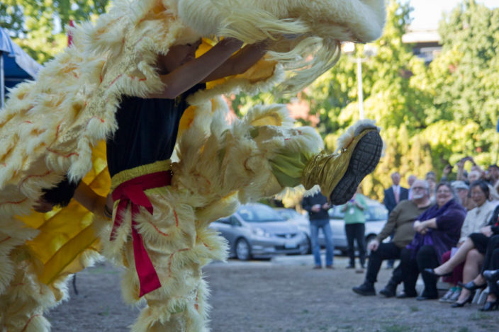 lion dance performer in yellow costume kicking his leg forward