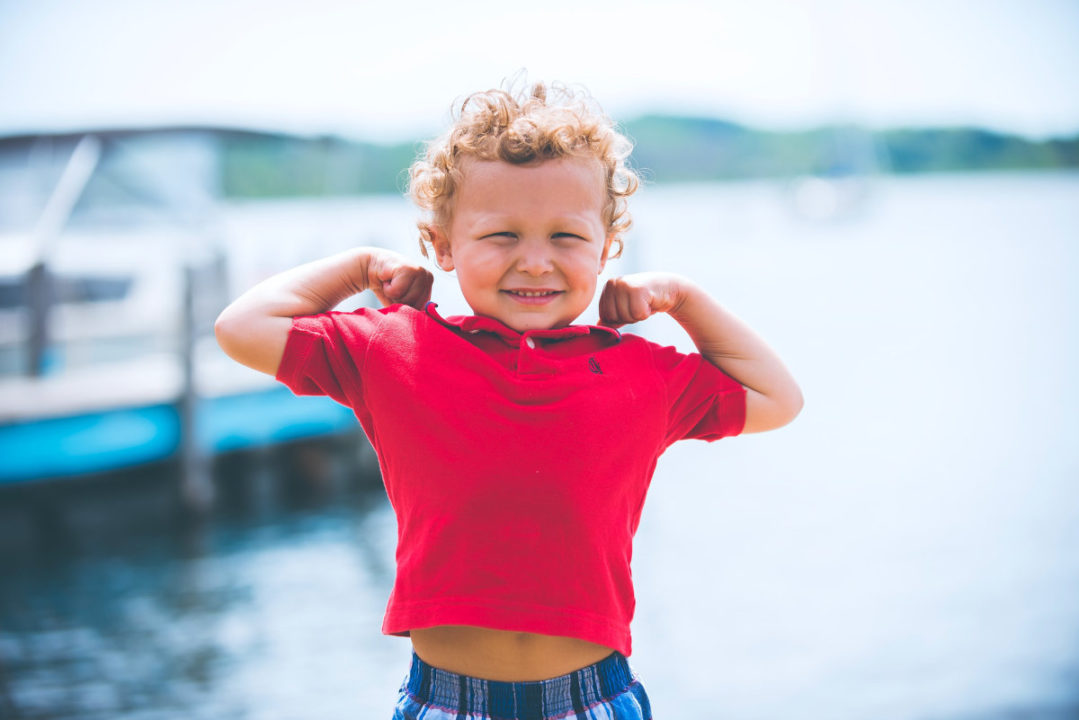 little boy flexing muscles and grinning