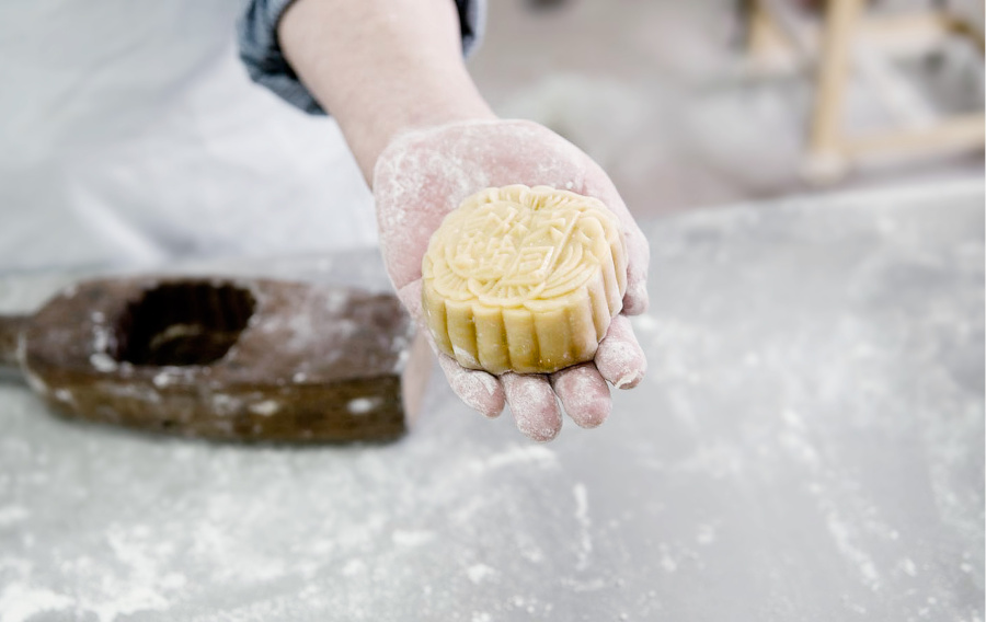 chef's hand holding a traditional chinese mooncake