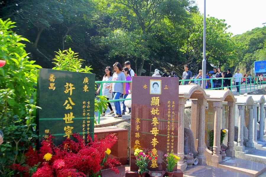 crowds hike in a mountain beside grave stones in hong kong