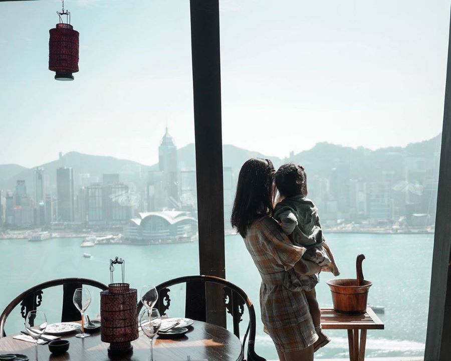 Hutong overlooks Victoria Harbour. A mother, who is carrying her small daughter, can see the Hong Kong Island skyline and ferries going across the harbour.