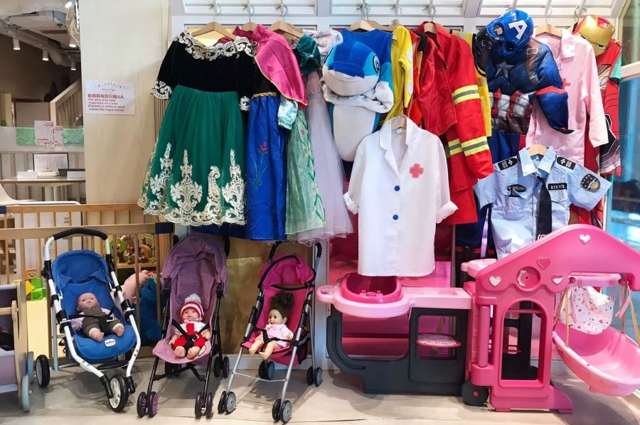 The dress-up station at Origami Kids Cafa has several costumes for children to choose from. There are princess outfits, a firefighter's uniform, a policeman's uniform, a doctor's and nurse's coat, and many superhero costumes. There are other toys as well, such as strollers with dolls and a bedroom set. 