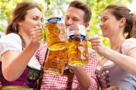 friends clinking beer mugs together at oktoberfest