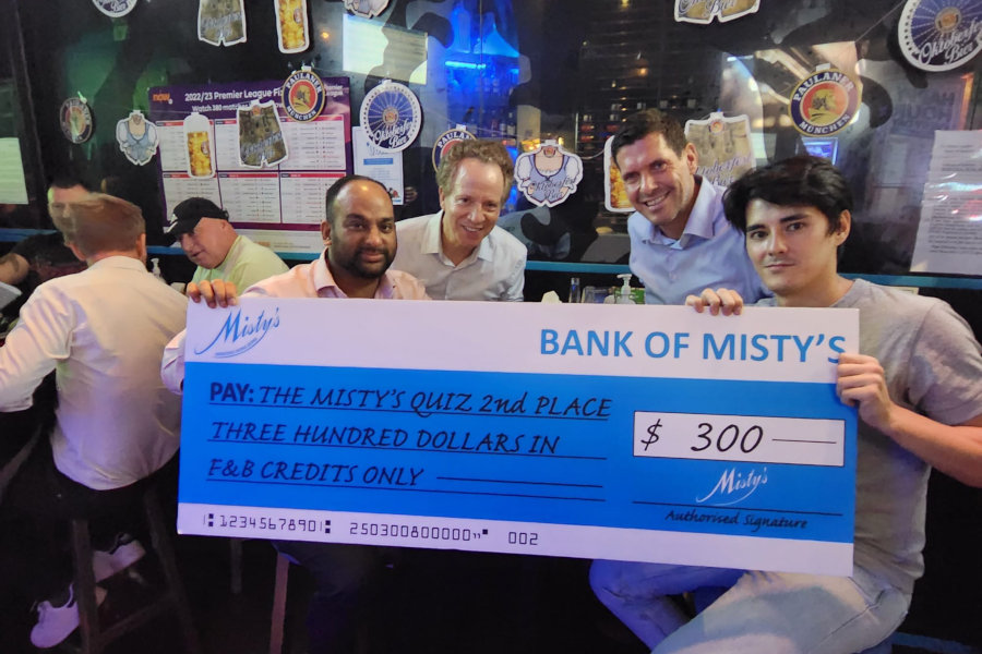 trivia night winners hold cheque at misty's pub hk