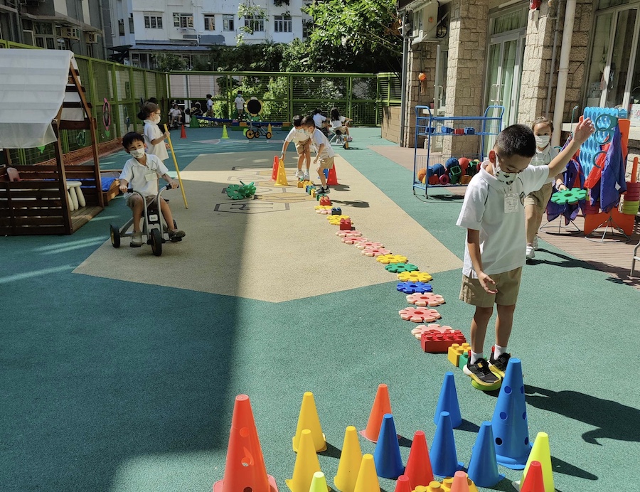 Children exploring different activities in the outdoor play space at HKCA Po Leung Kuk School