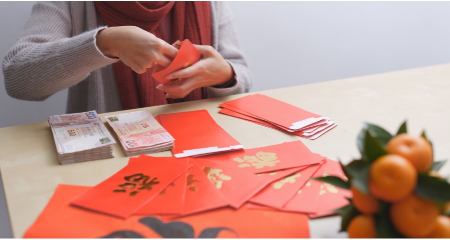 woman putting hong kong money into red pockets for chinese new year
