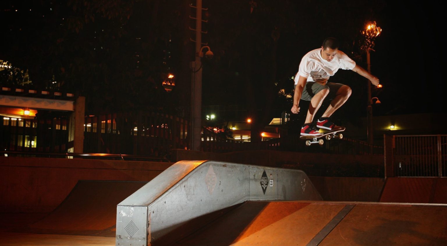 A skateboarder performs a trick at night.
