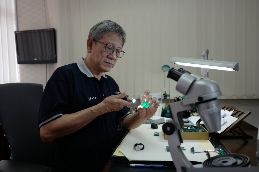 Biron Gems founder, Louis Lo, using a light to look at a lab grown emerald