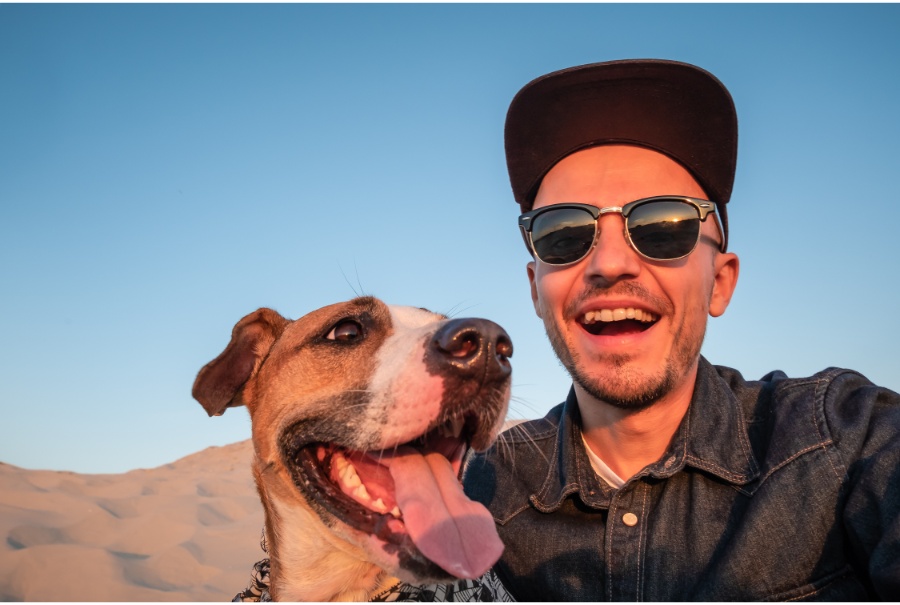 man taking a selfie with his dog in the desert