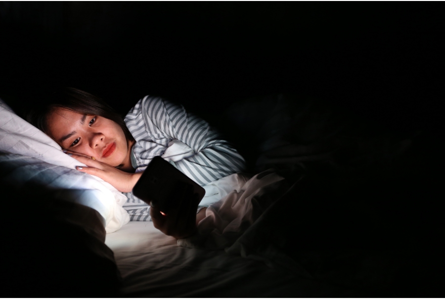 woman using a bright phone in bed