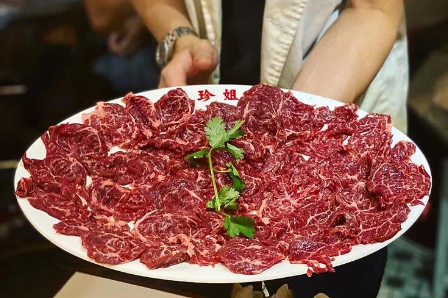 holding a giant plate of yellow beef, with a stem of coriander put on top as decor