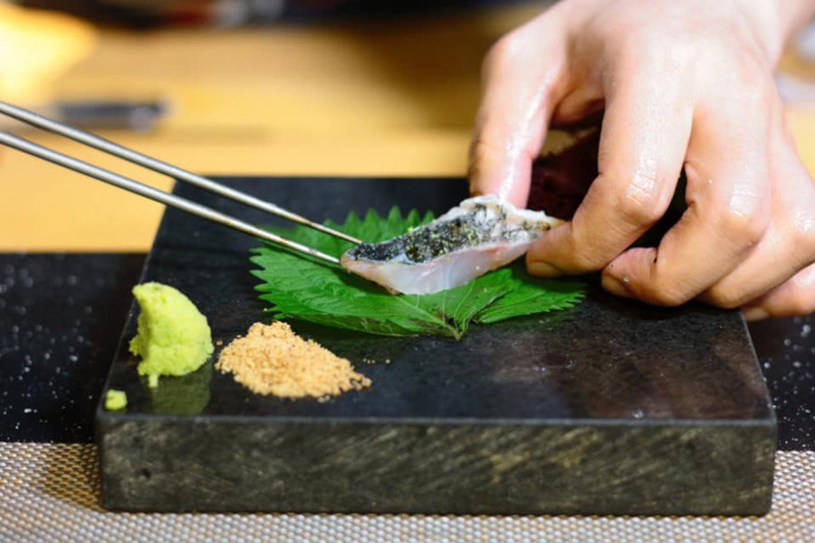 japanese sushi chef delicately placing a piece of sashimi on a block at chutsuki sushi omakase