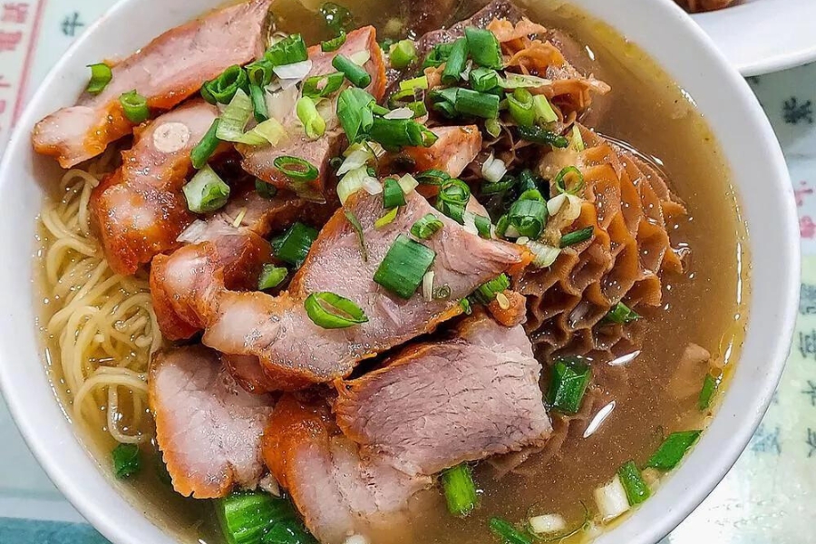 a bowl of soup noodles with braised beef brisket and oven-grilled bbq pork