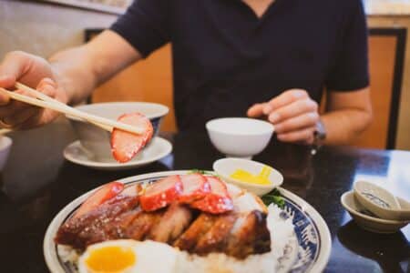 person eating hong kong bbq meats at a hong kong restaurant