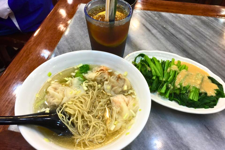 a bowl of wonton bamboo noddles, a plate of steamed choi sum with fermented beancurd and a glass of cold lemon tea