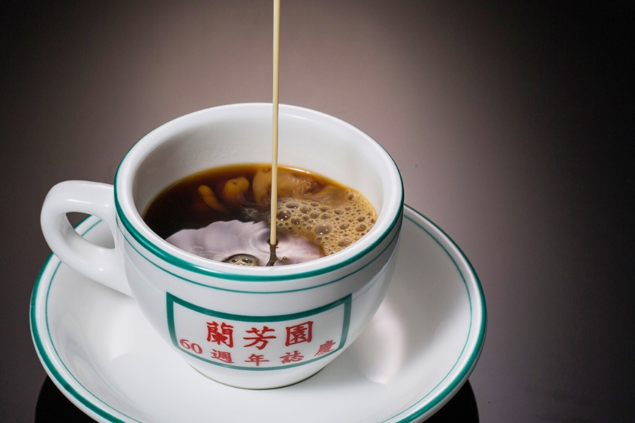 pouring milk into black tea in a Lan Fong Yuen 60th anniversary special tea cup