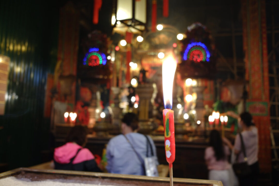 candle offering burning at the main altar of man mo temple sheung wan
