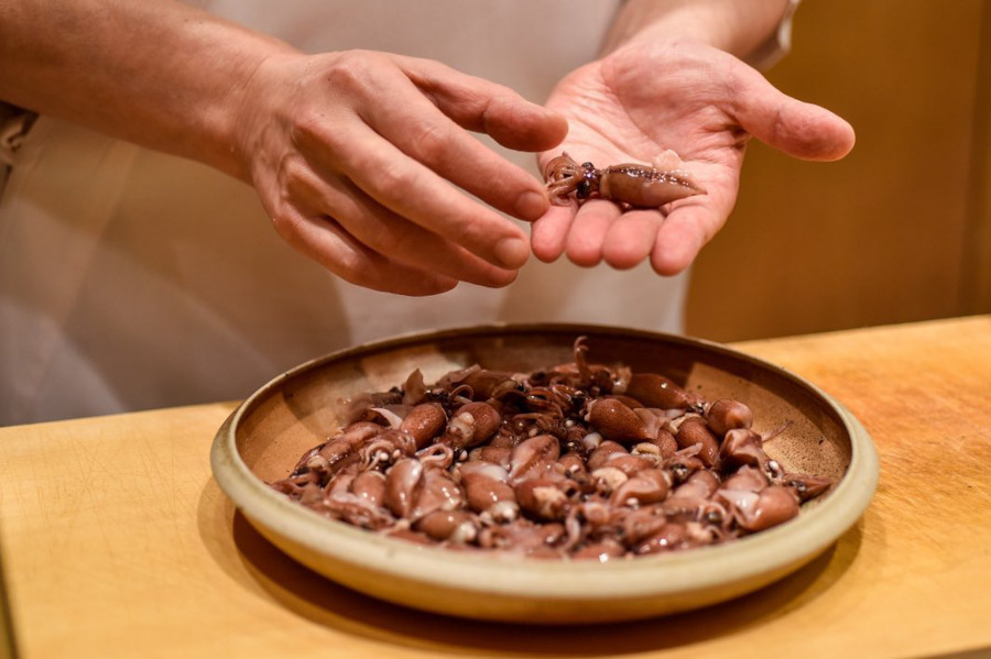 chef handling mini octopus at omakase in sushi shikon