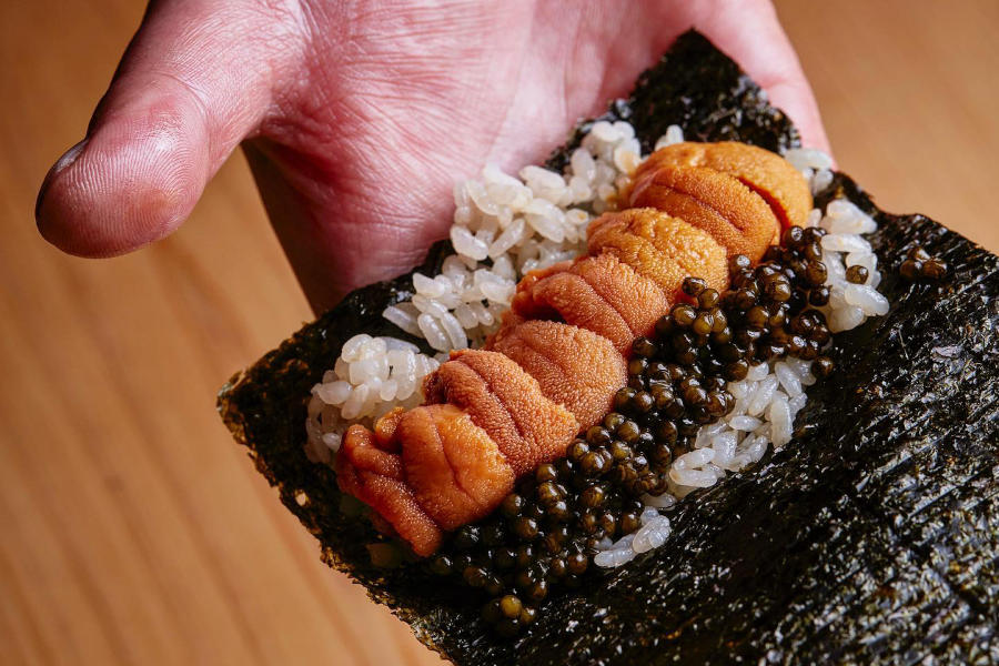 sushi chef holding urchin and caviar hand roll at umi hong kong