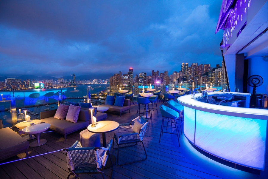 The outdoor rooftop terrace of SKYE overlooking the harbour with a blue-illuminated bar on the right