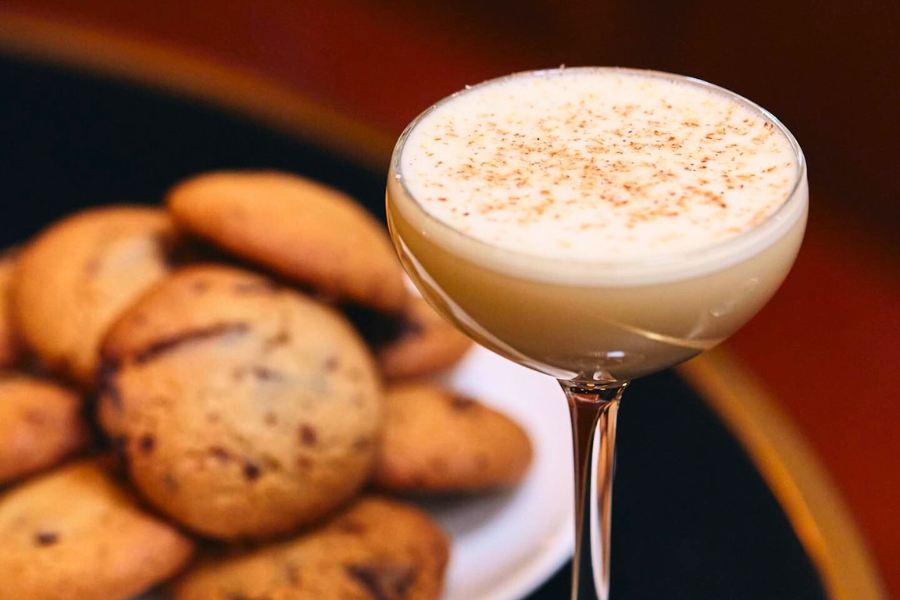 A glass of cocktails next to a plate of The Diplomat's signature freshly baked cookies, served free at night. 