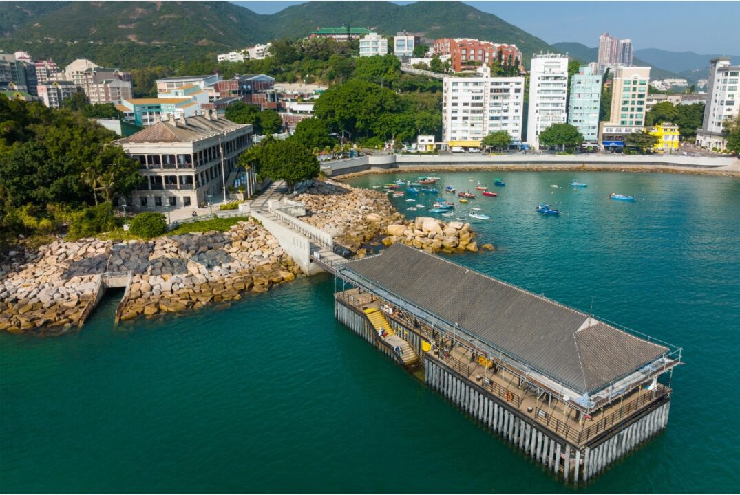 An aerial view of Stanley Promenade in Hong Kong. There is a view of the bay and buildings on the background.