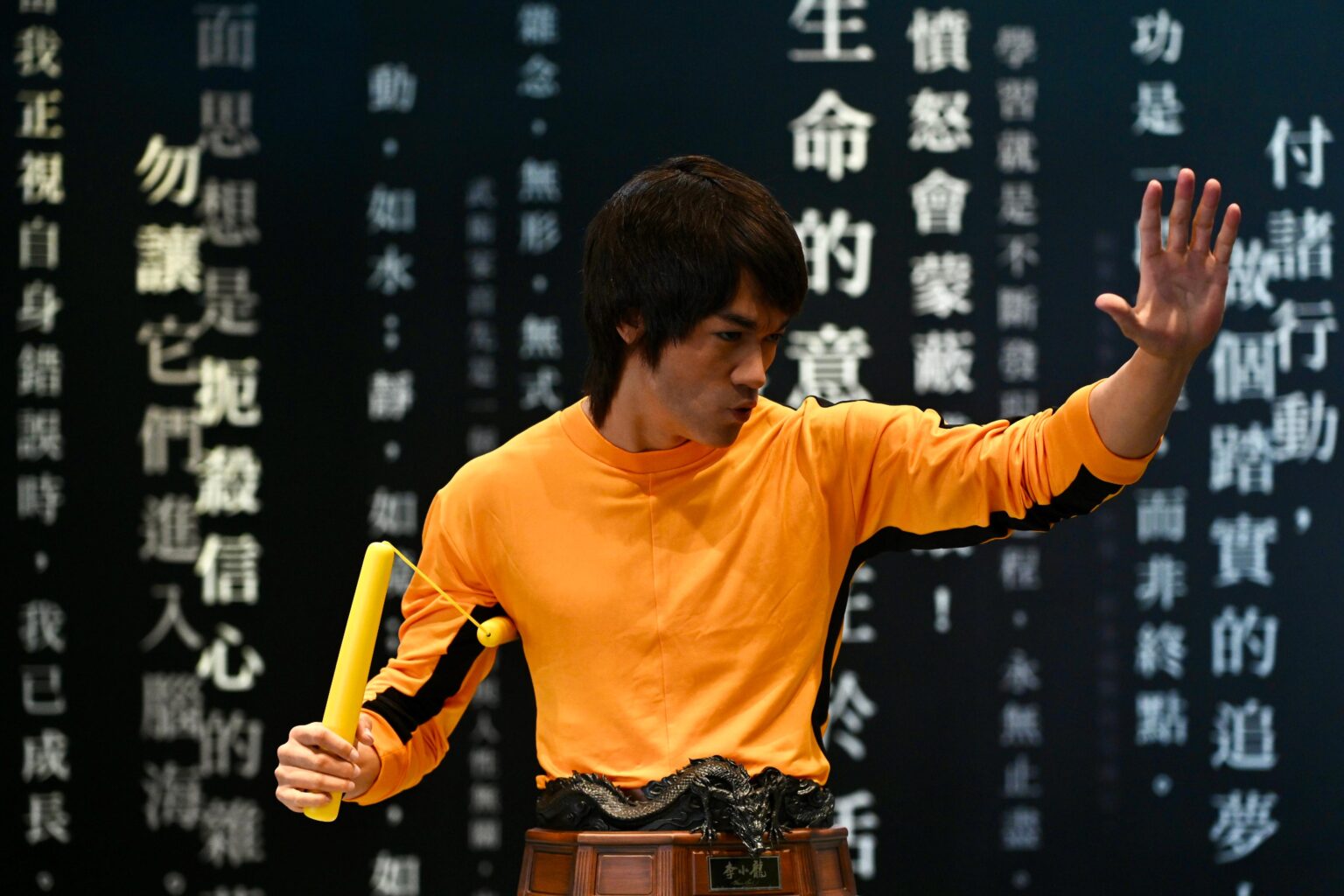 A life-size bust of Bruce Lee at the Hong Kong Heritage Museum. The replica of Bruce Lee is wearing a yellow long-sleeved short and is holding nunchucks.