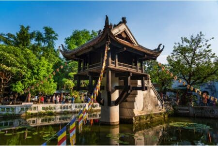 HK Express Is Offering HK$0 Fare Tickets Between Hong Kong & Hanoi From July 17-19 A low-angle view of the One Pillar Pagoda in Hanoi, Vietnam. The pagoda has banners suspended from its roof, and the stairway into the structure can be seen in the background.