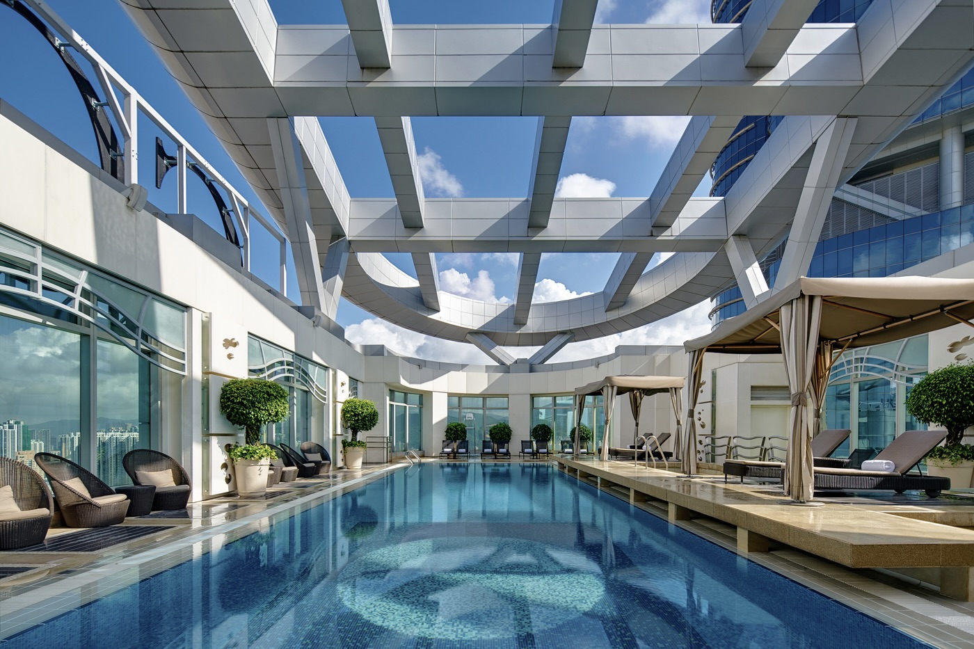 The 20-metre-long indoor swimming pool at the Cordis Hong Kong has deck chairs under cabanas and patio chairs.