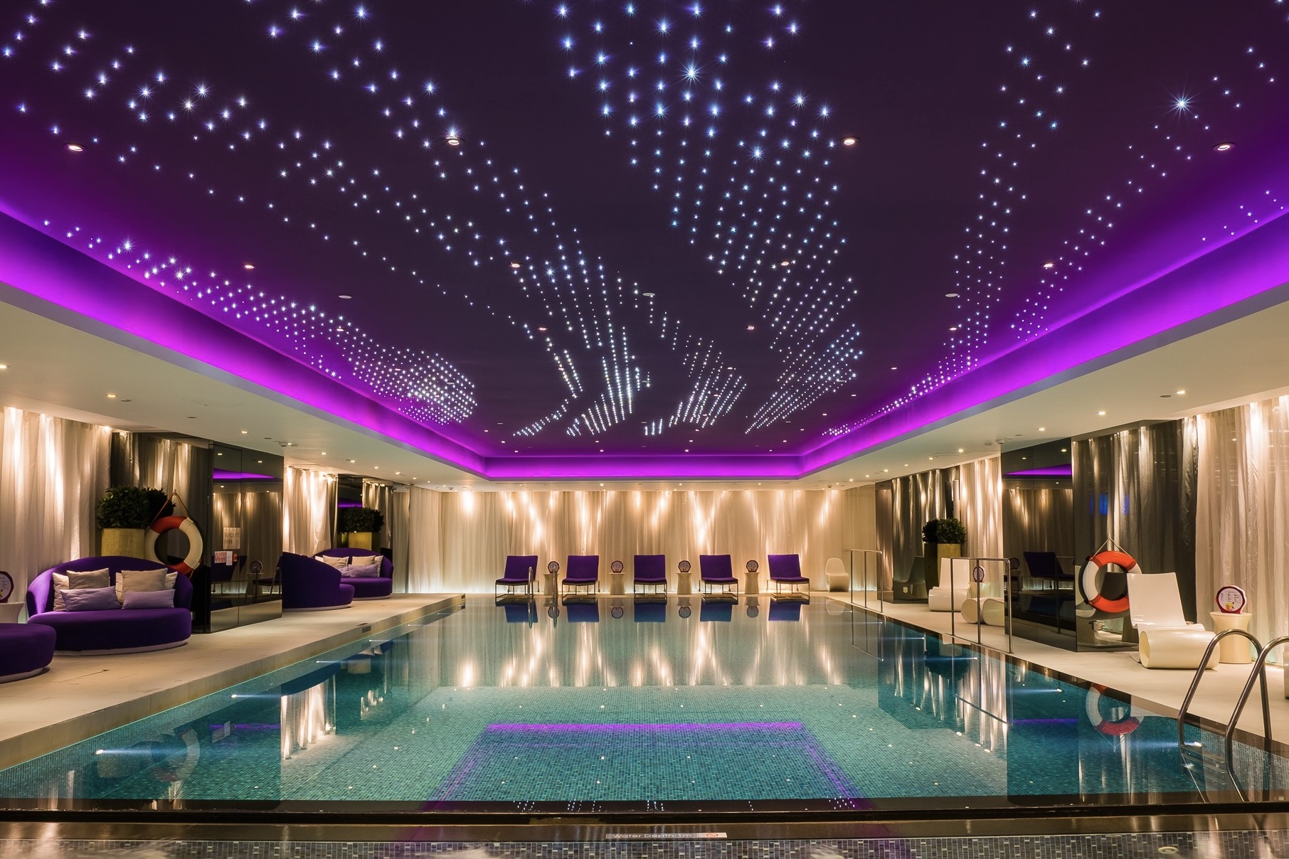 The indoor swimming pool at The Mira Hong Kong has an indoor lighting system that complements the ceiling lighting. The matching chaise lunges and sofas add to the air of elegance.