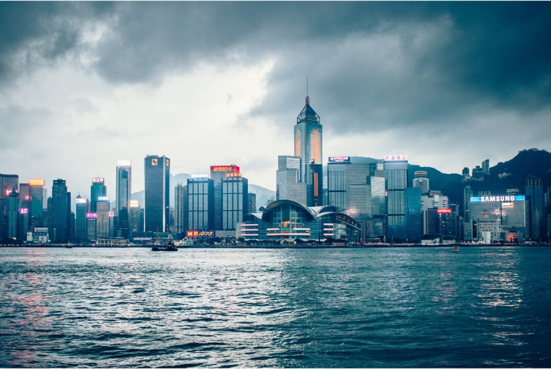 The Hong Kong Island skyline in the evening. The sky is overcast and the seas of the harbour are rough.