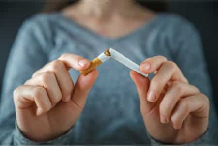 Stub Out Smoking In Public By Staring, Says Hong Kong’s Secretary For Health A woman breaks a cigarette in two. She is wearing a grey sweater and her face is unseen.