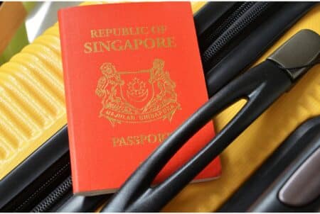 Singapore Now Has World’s Most Powerful Passport, Hong Kong Passport Moves Up To No. 17 Spot A red Singapore passport tucked into the handle of a yellow-and-black suitcase.