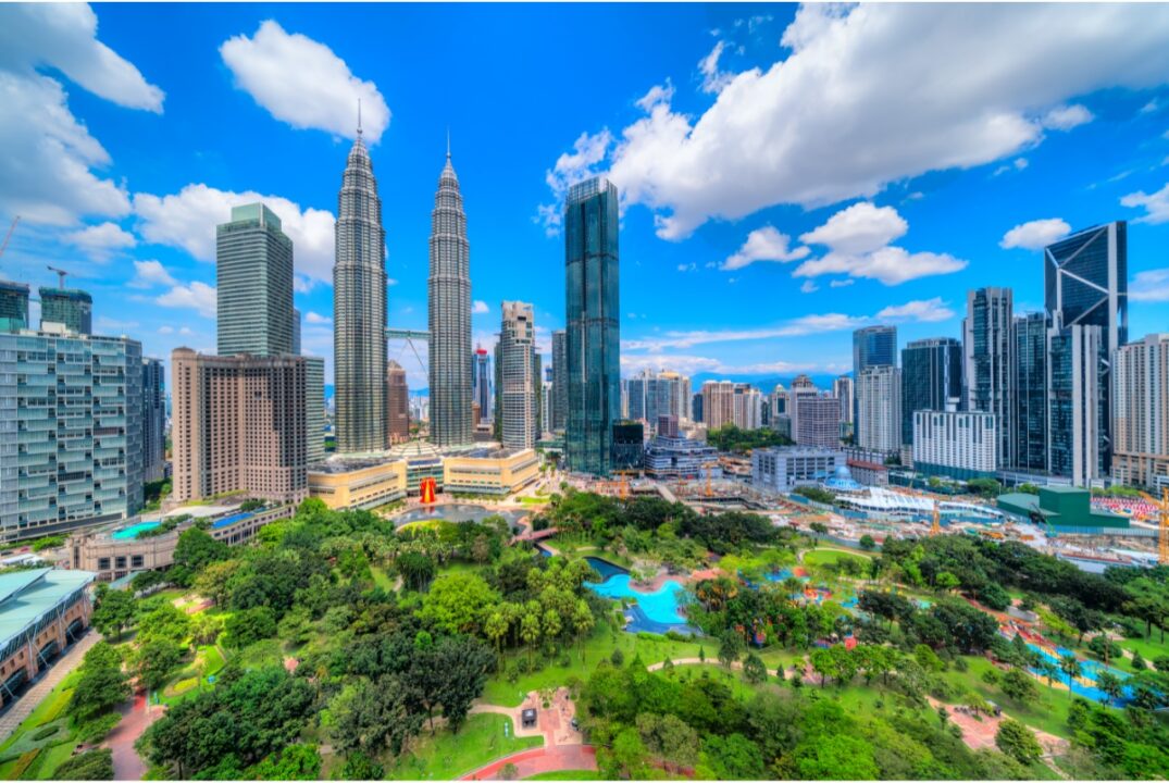 A view of the Kuala Lumpur skyline with the Petronas Twin Towers and other skyscrapers in the background and the KLCC park in the foreground.